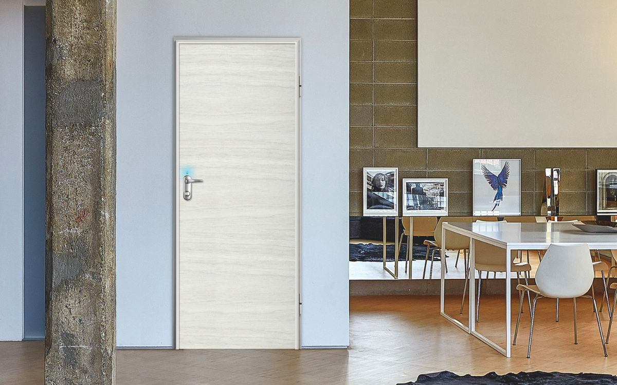 La porta blindata domotica Dierre Next Elettra nel modello Synergy con rivestimento effetto rovere chiaro.